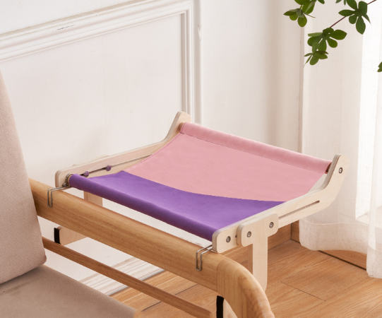 Pink and purple cat hammock bed securely hanging from a wooden bed frame.