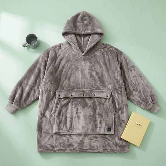 Hoodie blanket laid flat showing the soft flannel texture, oversized front pocket, and relaxed wearable blanket design.