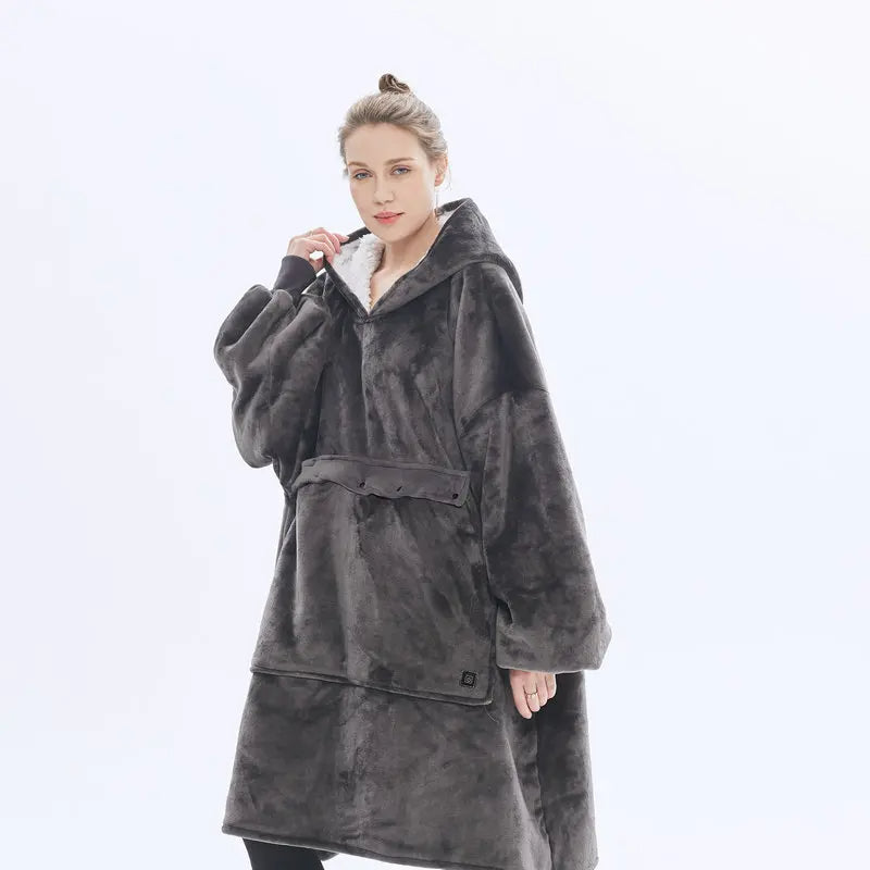 Woman wearing the oversized blanket hoodie in dark grey, showing the full-length wearable blanket design with front pocket.