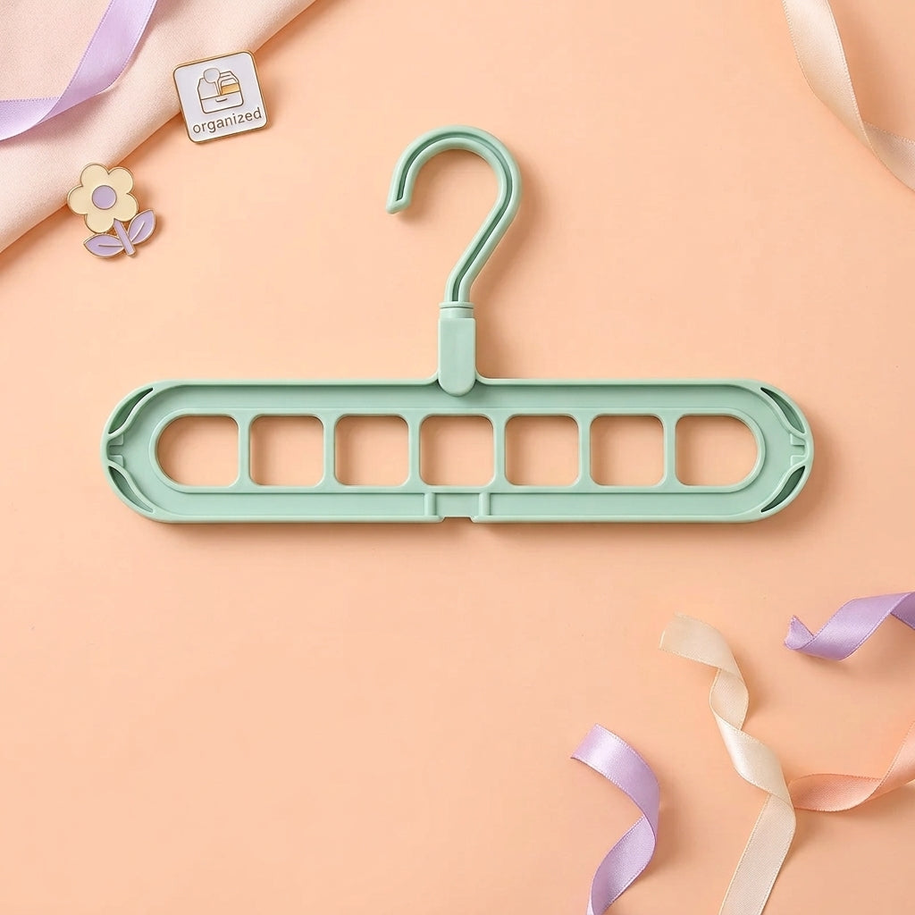 Green space saving coat hangers shown on a peach background, displaying the 9-hole cascading design that holds multiple garments in one slot.