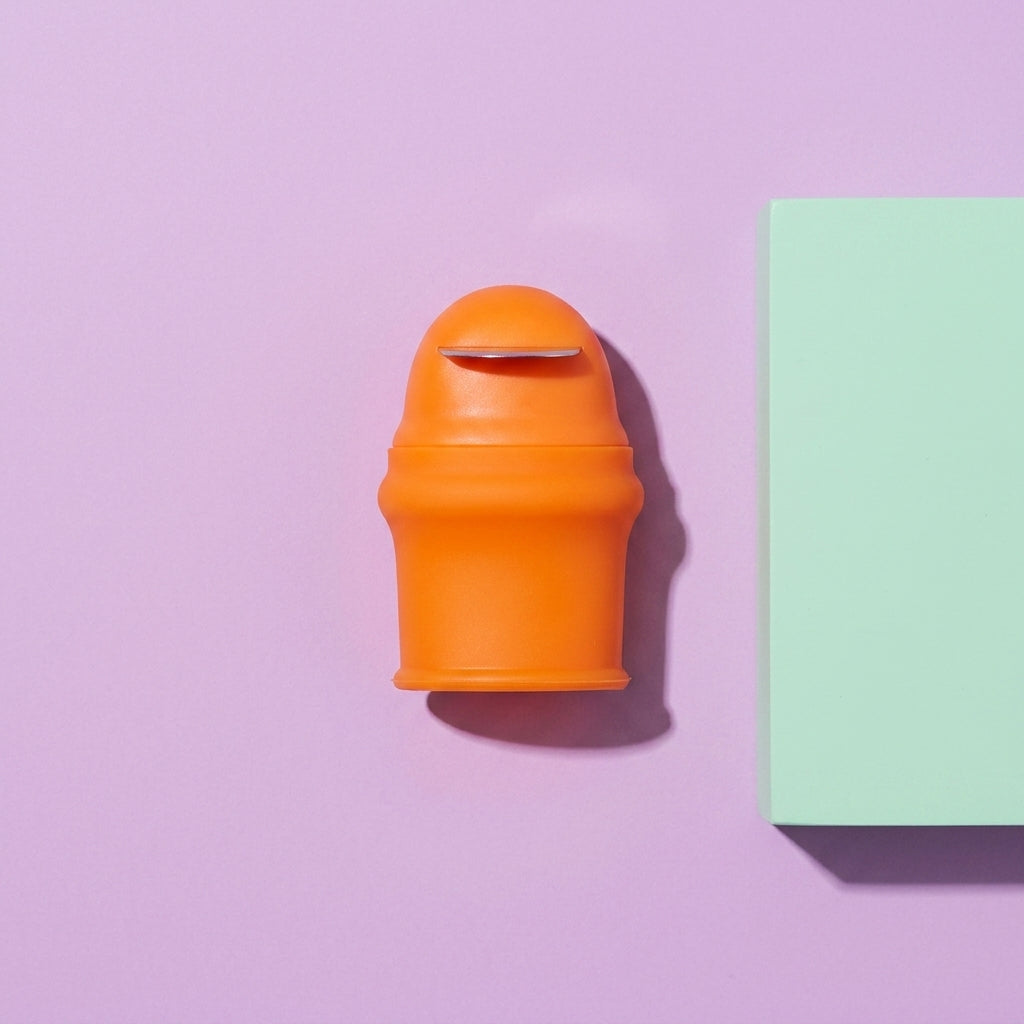 Orange silicone thumb knife shown on a purple background, featuring the stainless steel arc blade for garden harvesting.